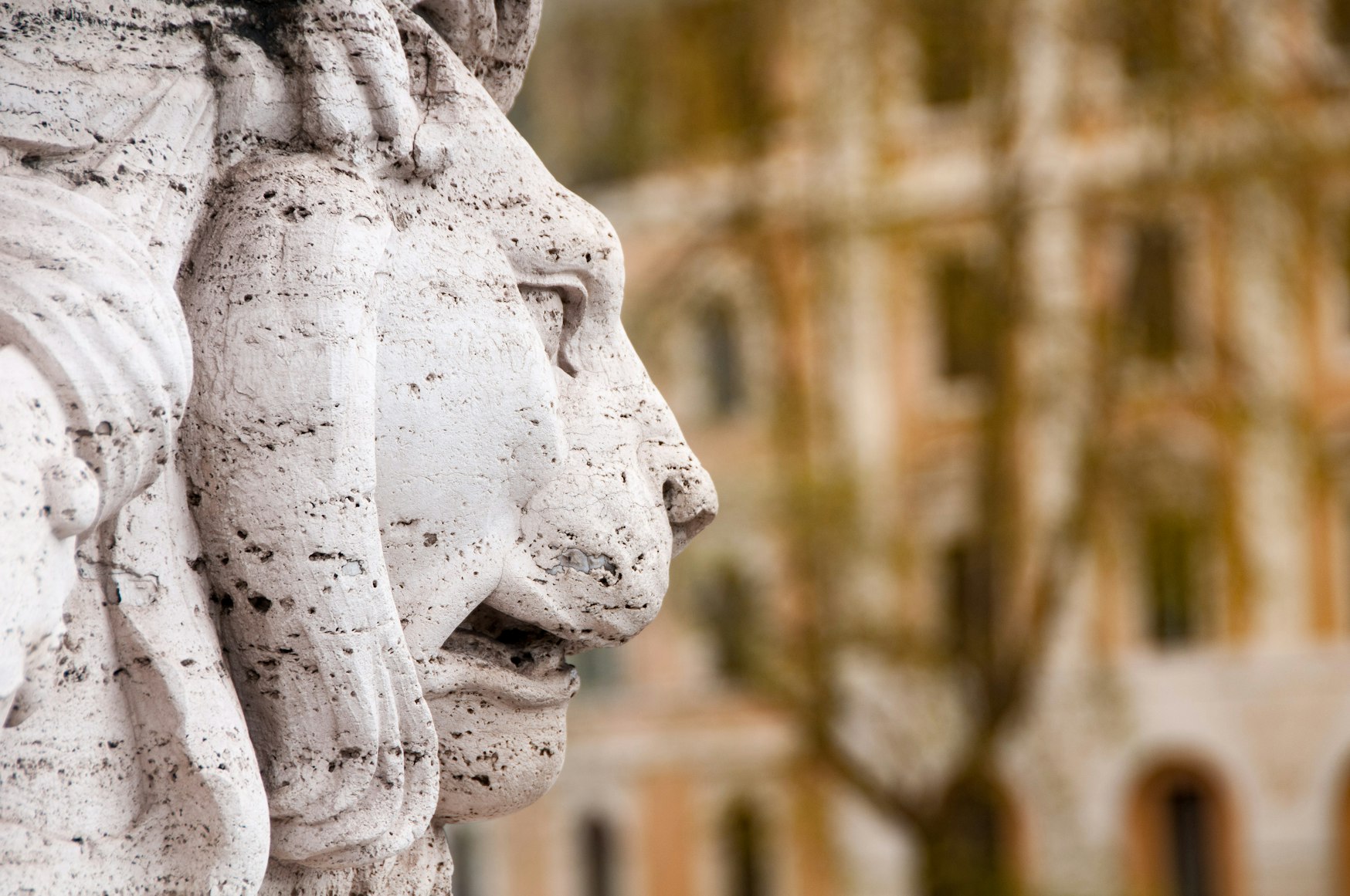 Stone lion sculpture in profile against a blurred classical building facade, representing institutional scrutiny and the unseen compliance checks shaping UHNW banking access