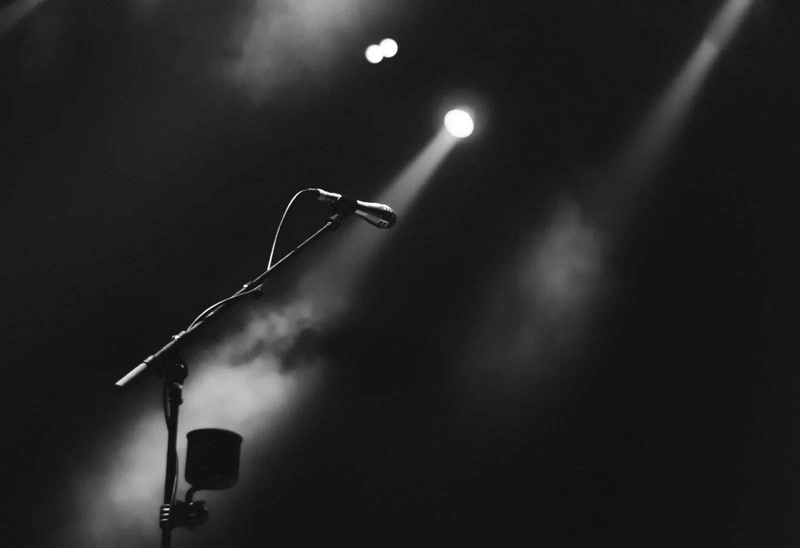 A single microphone lit by a stage light through haze - representing the editorial voice that gives earned media its credibility