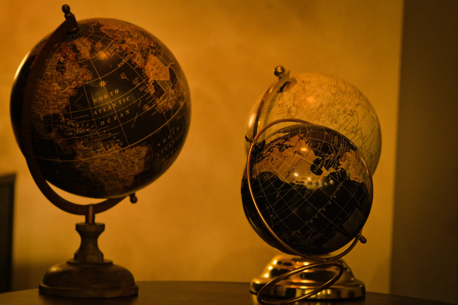 Two ornate vintage globes side by side under warm light - representing the constant, observed world the next generation will inherit